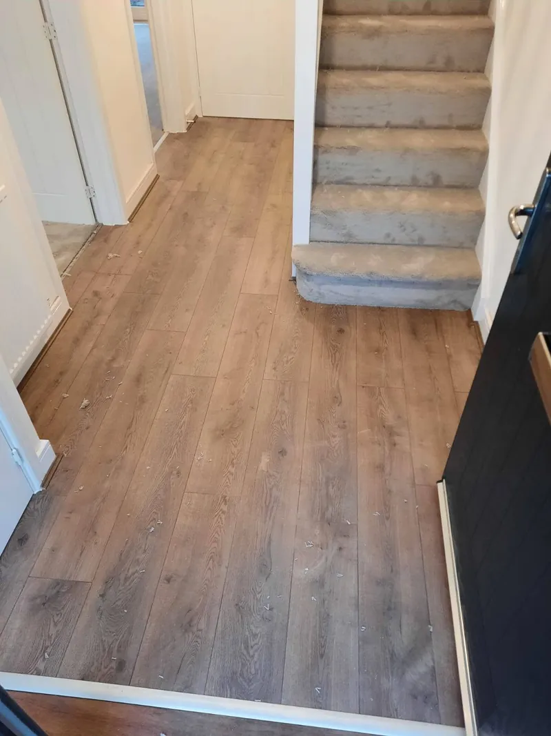 Plank flooring in the hall with carpet up the stairs