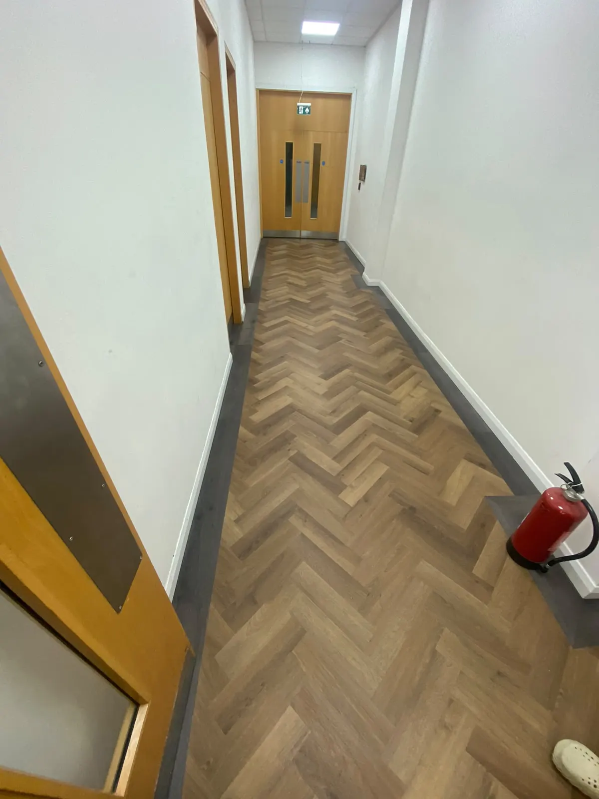 Herringbone LVT corridor framed with a contrasting border