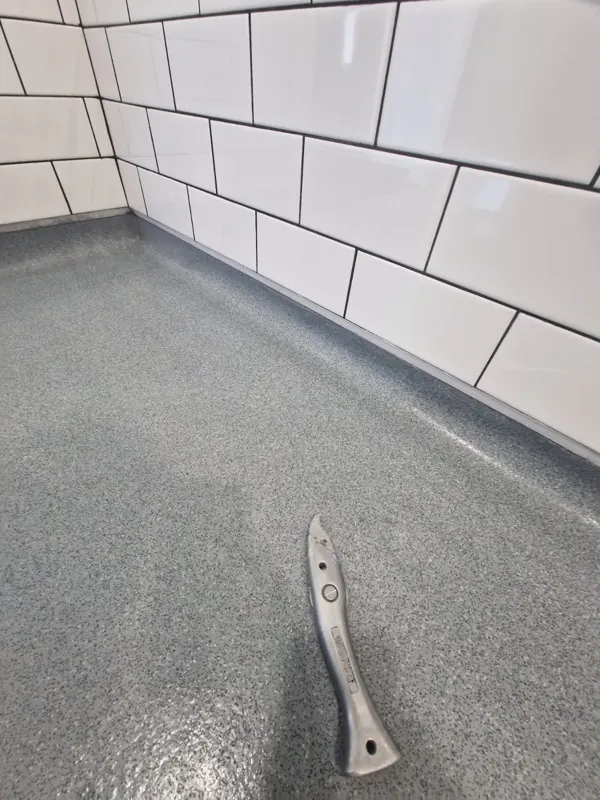 Safety vinyl coved up to the wall tiles