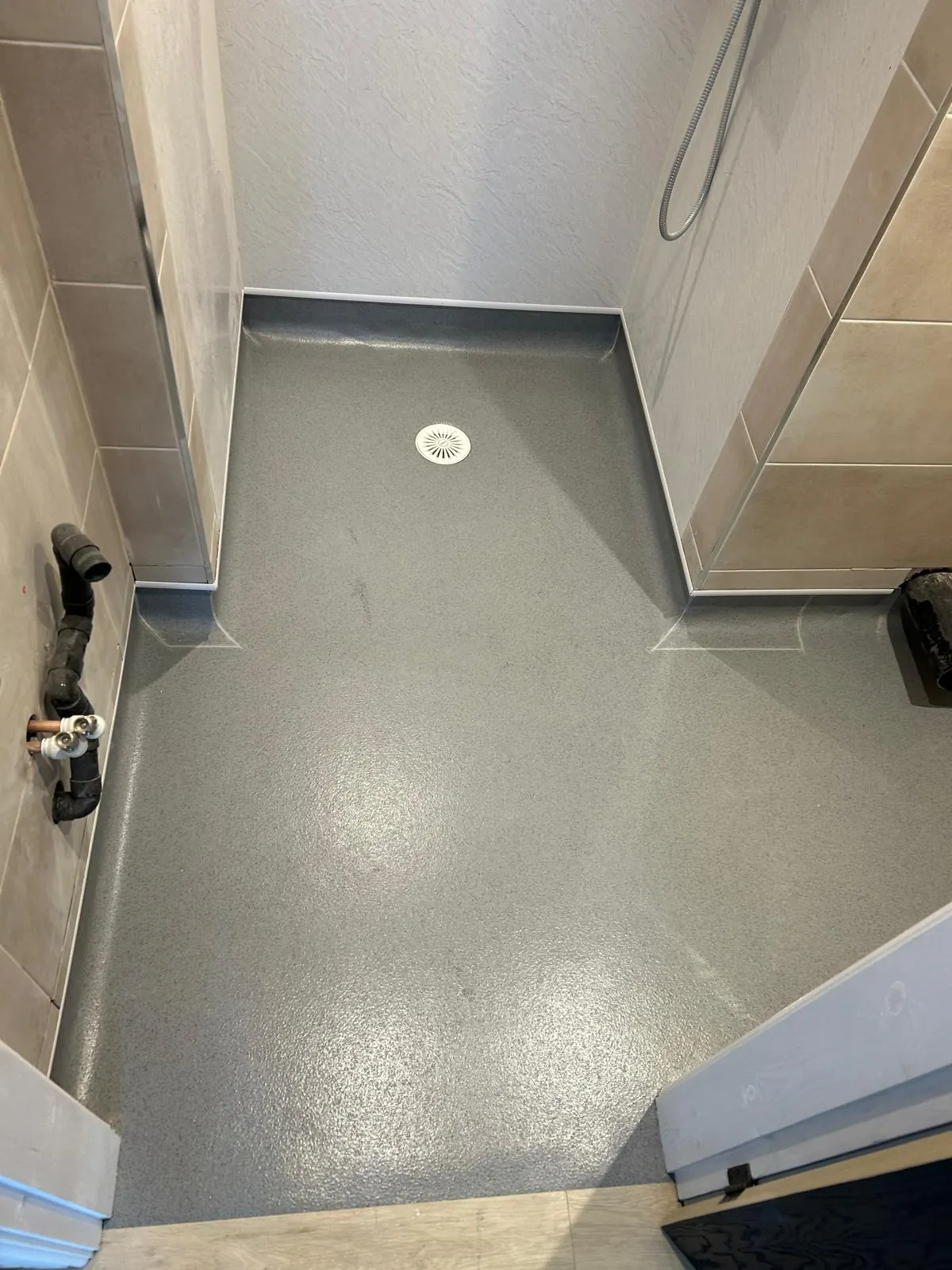 Wet room finished in safety vinyl, coved at the walls and dressed into the drain